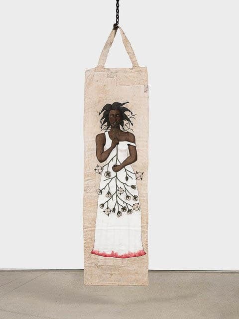 Tall, narrow artwork depicting a woman in a white dress with a branch and leaf pattern, hanging from a chain.
